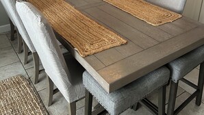 Un espace repas avec une longue table, des bancs rembourrés et un set de table en fibres tressées.