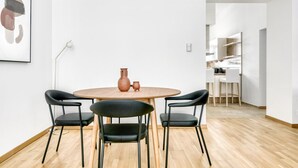 Et moderne spiseområde med et rundt træbord, fire sorte stole og en vase.