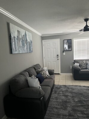 Relax in this stylish living room with a sofa, abstract cityscape painting, and a cozy reading nook.