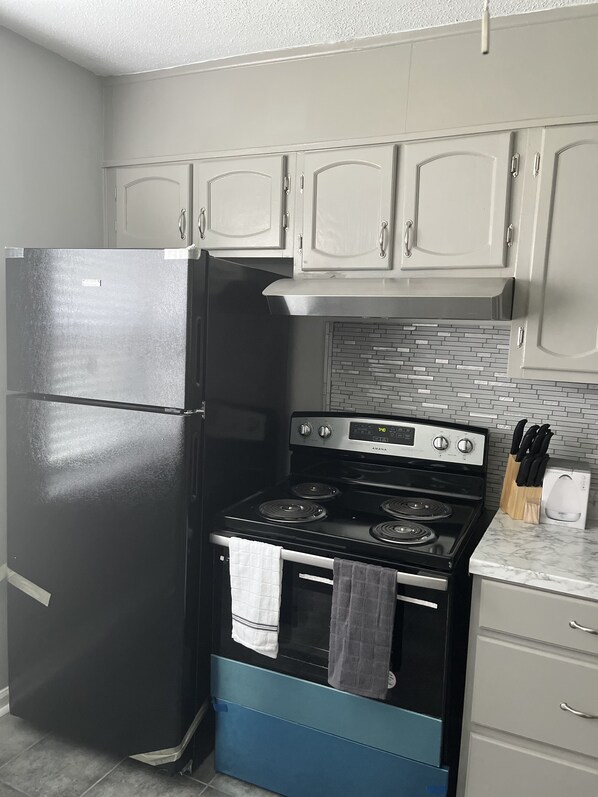 Kitchen area with refrigerator, stove, and microwave, perfect for cooking and meal preparation.