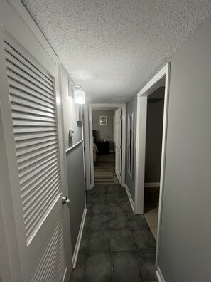 Stylish hallway with doors leading to various rooms, featuring a textured ceiling and tiled floor.