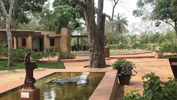 Un patio con una fuente, una estatua y un edificio con una pérgola.
