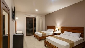 Habitación de hotel con dos camas, un escritorio, un televisor y un ventanal corredizo al exterior.