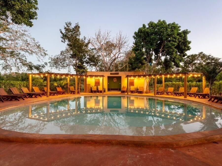Uma área de piscina com espreguiçadeiras e um espaço de estar coberto.