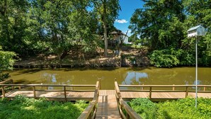 A wooden bridge leading to a river with a wooden dock.