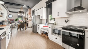 A modern kitchen with stainless steel appliances, white cabinetry, and a wooden floor.