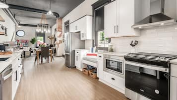 Modern kitchen with stainless steel appliances, white cabinetry, and a dining area.
