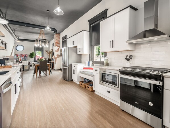 Modern kitchen with stainless steel appliances, white cabinetry, and a dining area.