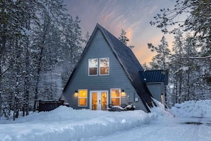 A house with a steeply pitched roof, a chimney, and a number '156' on the side.