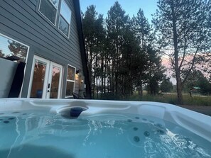 A hot tub in a backyard with a house and trees in the background.