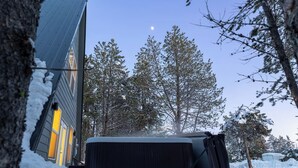 Een huis met een besneeuwde tuin, een grote boom en een heldere lucht.