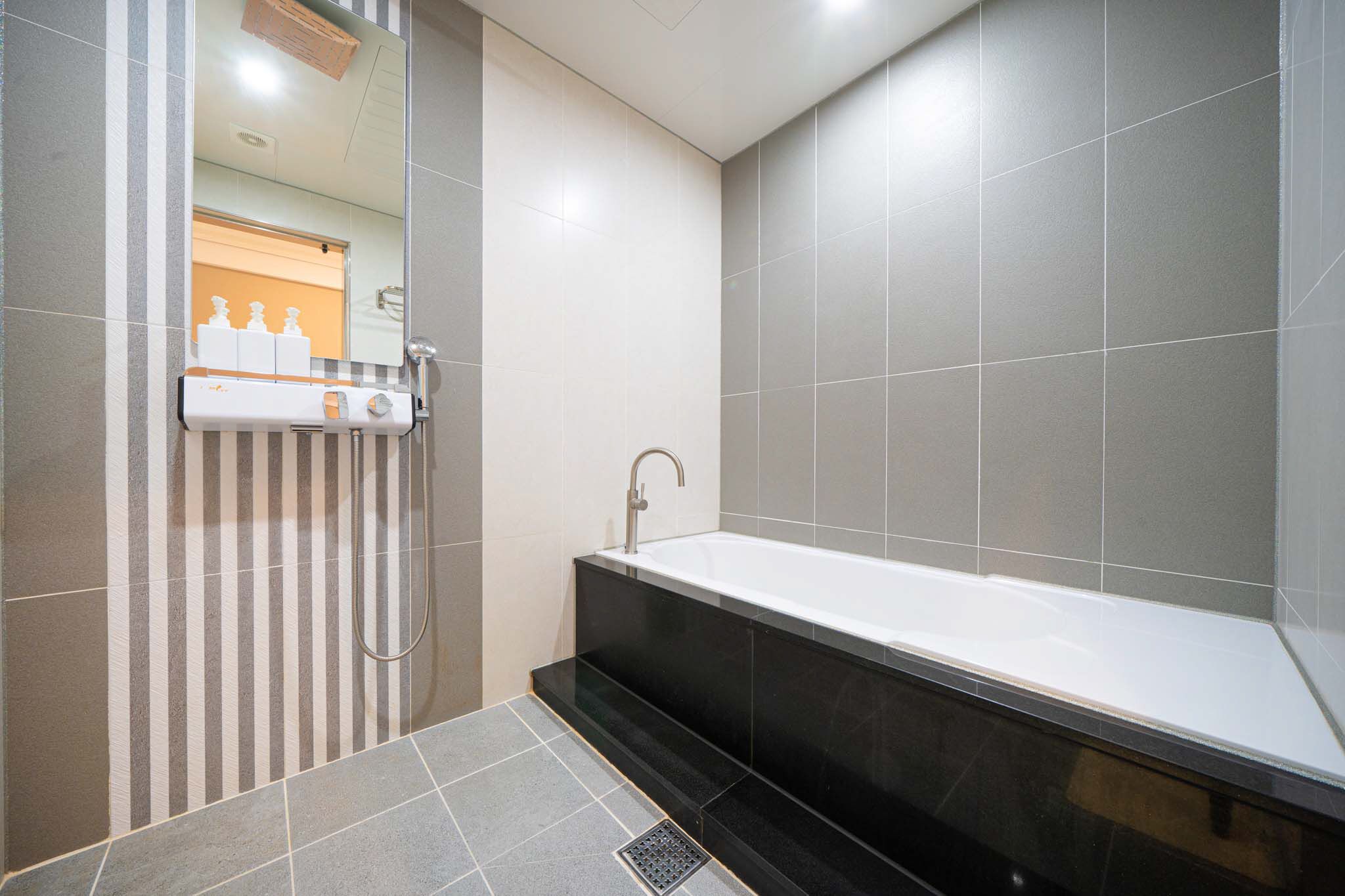 Un bagno moderno con una vasca da bagno ampia, una zona doccia e un portasacchi a righe.