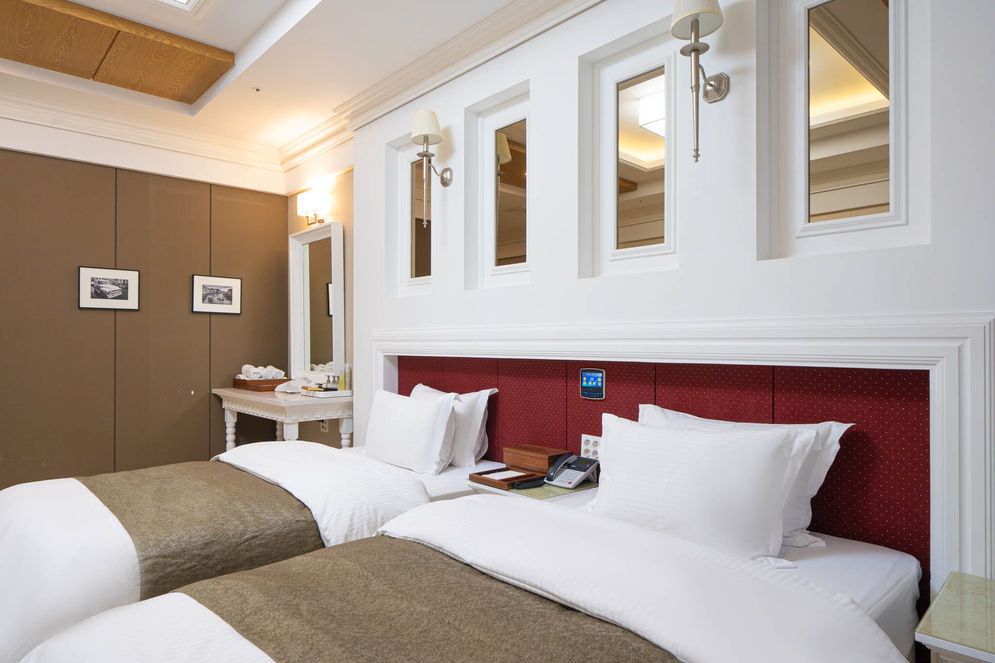 Una habitación de hotel con dos camas, un tocador con espejo y una mesita.
