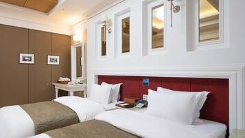 Una habitación de hotel con dos camas, un tocador con espejo y una mesita.