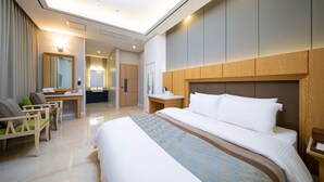 A hotel room with a large bed, a desk with a chair, a mirror, and a wardrobe. - HOTEL CORE (Naju)