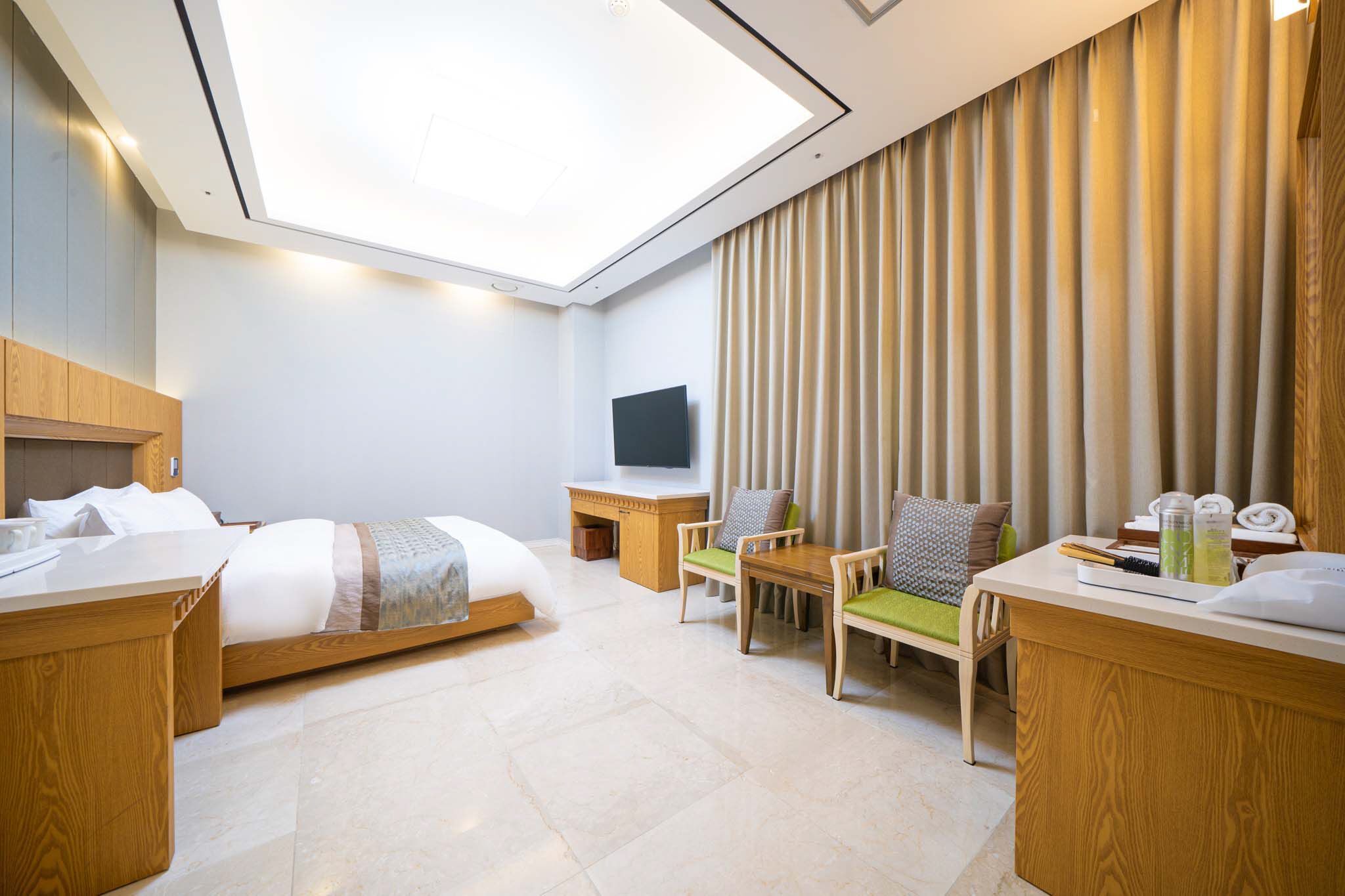 Una habitación de hotel moderna con tragaluz, cama, escritorio, televisor y zona de estar.