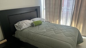 A neatly made bed with a green quilt, a white pillow, and a green accent pillow. - Cozy 2-bedroom condo, located in the center of the city.  (Ciudad de México)