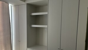 A bedroom with a bed, a wardrobe with open doors, and a window with a curtain. - Cozy 2-bedroom condo, located in the center of the city.  (Ciudad de México)