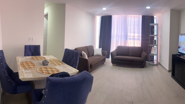 A living room with a dining area, a sofa, a TV, and a hallway. - Cozy 2-bedroom condo, located in the center of the city.  (Ciudad de México)