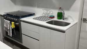 A modern kitchen with white cabinetry, a stainless steel stove, a sink, and a range hood. - Cozy 2-bedroom condo, located in the center of the city.  (Ciudad de México)