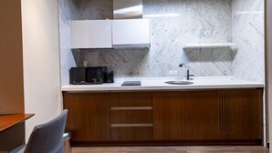 A modern kitchen with marble walls, wooden cabinets, and a built-in sink. - Merciel Hotel (Busan)