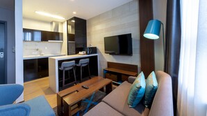 A modern living room with a sofa, a coffee table, and a TV mounted on the wall. - Merciel Hotel (Busan)