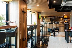 A modern bar area with high stools, a wooden accent wall, and a television screen.