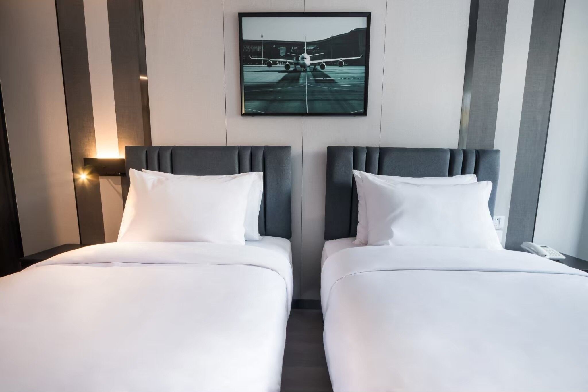 Habitación de hotel con dos camas, un ventanal grande y un cuadro colgado en la pared de un avión.