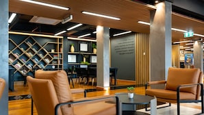 Une bibliothèque moderne avec des fauteuils en cuir, des étagères et une table basse.
