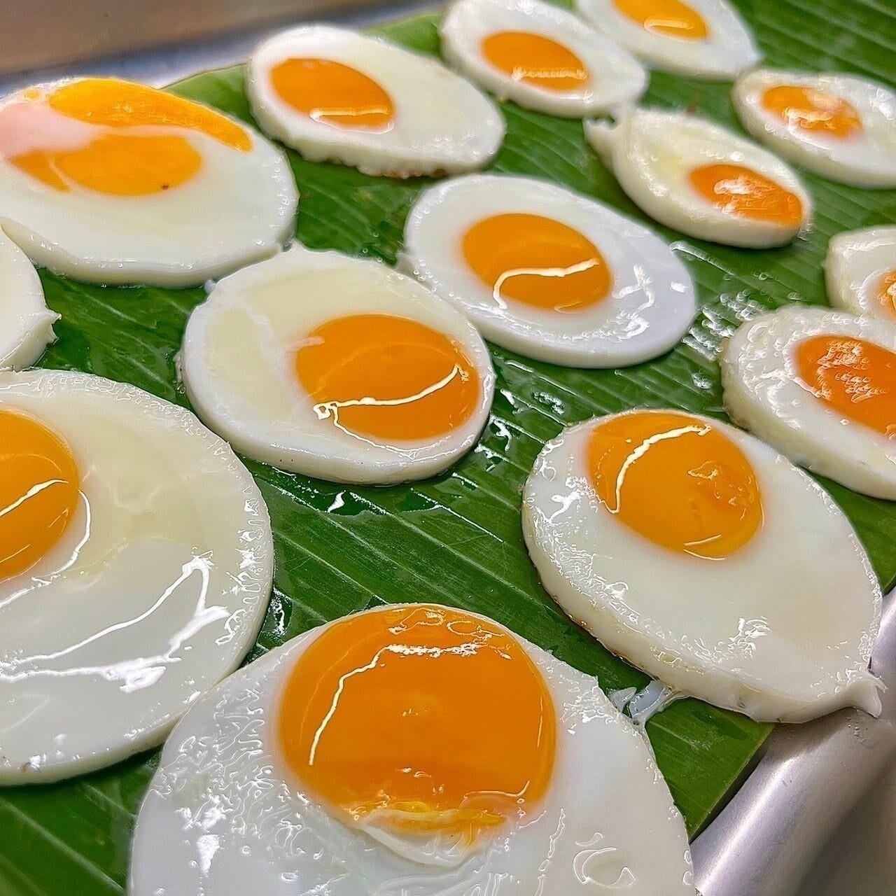A close-up of sunny-side-up eggs on a banana leaf.