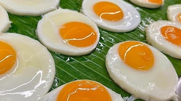 Un primer plano de huevos fritos con la yema líquida sobre una hoja de plátano.