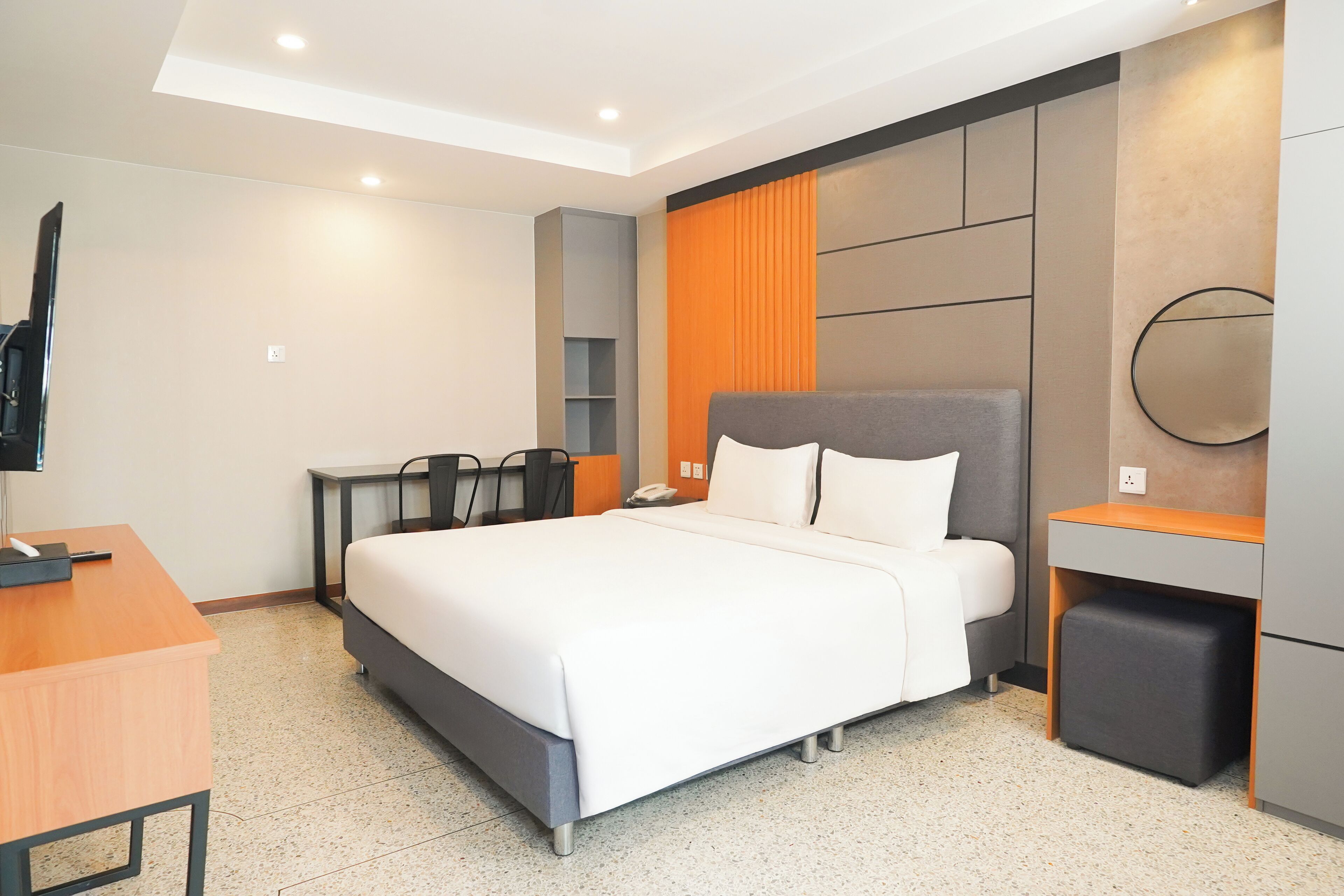 A modern hotel room with a large bed, a desk, and a TV.