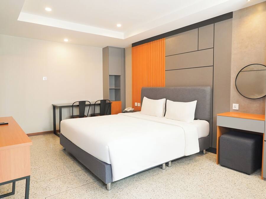 Una habitación de hotel moderna con una cama grande, un escritorio y un televisor.