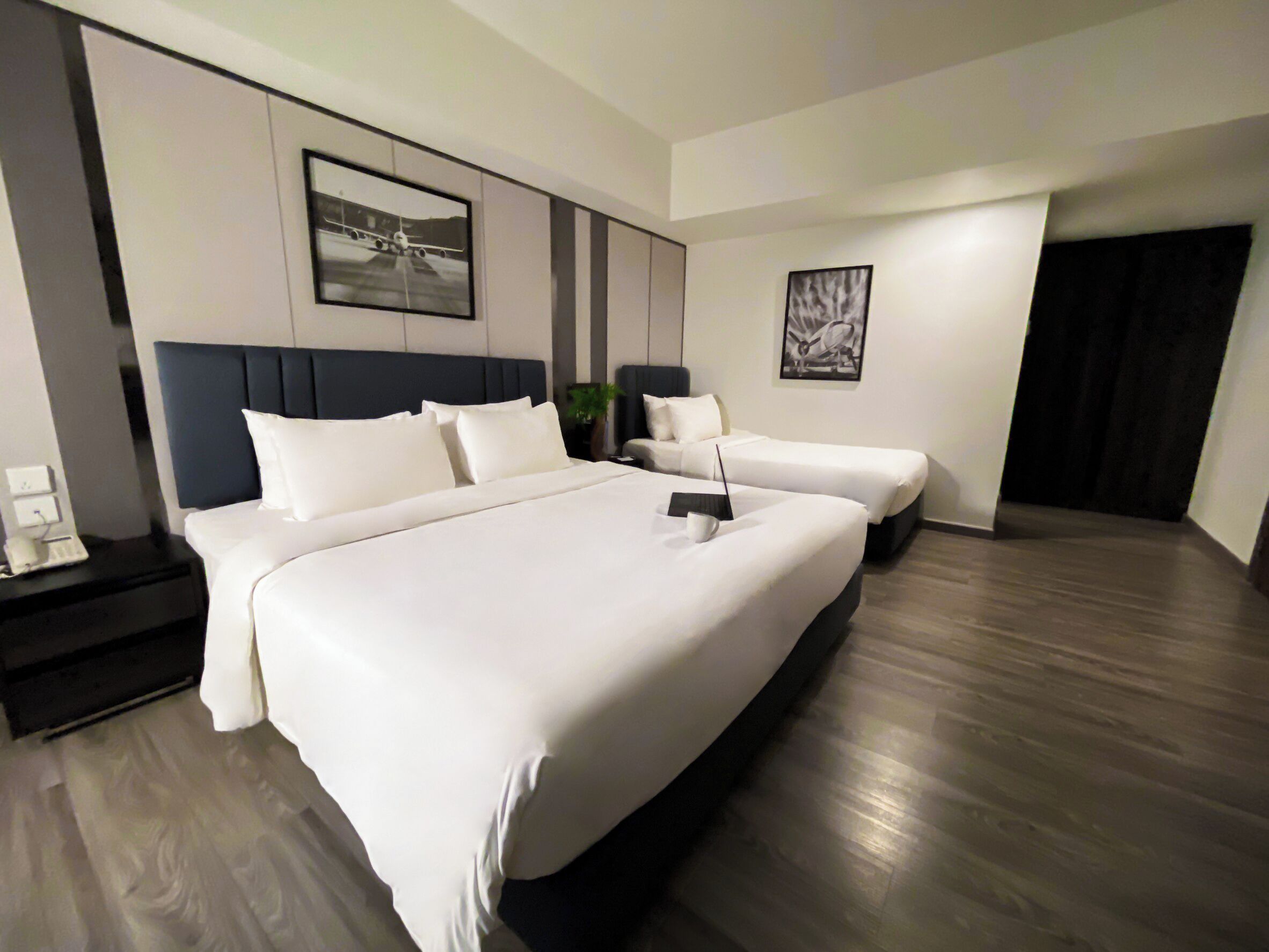A modern hotel room with a large bed, a desk, and a chair. There are two smaller beds in the room.