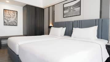 A modern hotel room with a large bed, a bedside table, a nightstand, and a wall-mounted lamp.