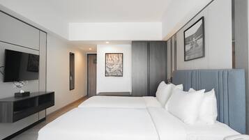 Una habitación de hotel moderna con una cama grande, un televisor de pantalla plana, una mesita de noche con un teléfono y una obra de arte enmarcada en la pared.