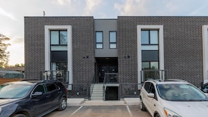A modern building with a brick facade, large windows, and a central entrance with steps. - Elegant Apartment,  5mins from the Falls (Niagara Falls)