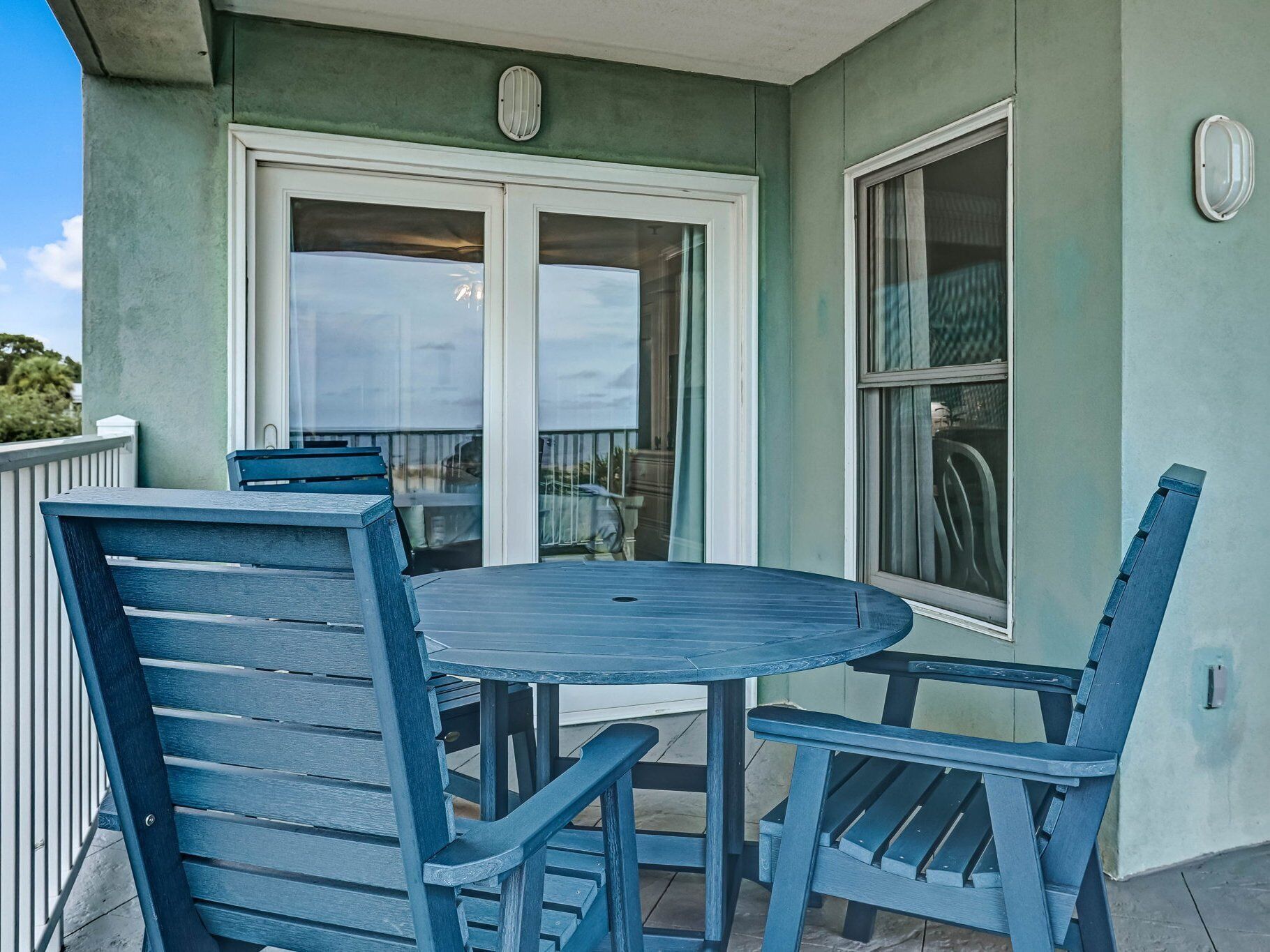 Une terrasse avec une table ronde et quatre chaises bleues.