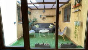 A cozy indoor patio with a grey sofa, a small round table, and potted plants. - Sunset Beach 4 Floor Villa 200m to Beach+Fast WIFI (Corralejo)