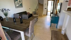 A spacious living area with a wooden dining table, patterned chairs, and a staircase leading to an upper floor. - Sunset Beach 4 Floor Villa 200m to Beach+Fast WIFI (Corralejo)