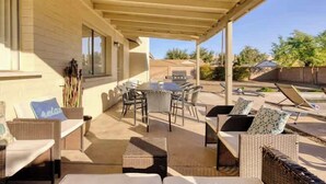 Un patio al aire libre con mobiliario de mimbre, una mesa y una parrilla.