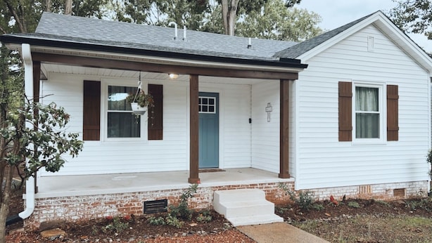 A single-story house with a front porch, a blue door, and brown shutters. - Comfy vintage cottage in beautiful small town--7mins from everything. (Newton)