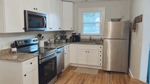 A modern kitchen with white cabinets, stainless steel appliances, a microwave, stove, oven, and refrigerator. - Comfy vintage cottage in beautiful small town--7mins from everything. (Newton)