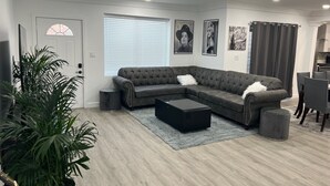 Ein modernes Wohnzimmer mit einem Ecksofa, einem Couchtisch und einem Essbereich.