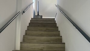 Eine Holztreppe mit Metallgeländern, die zu einer Zwischenebene führt.