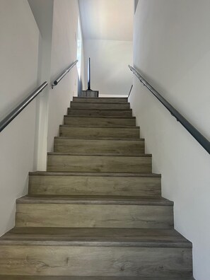 A wooden staircase with metal handrails, leading to a landing. - Spacious Modern Grey Home (Midway City)