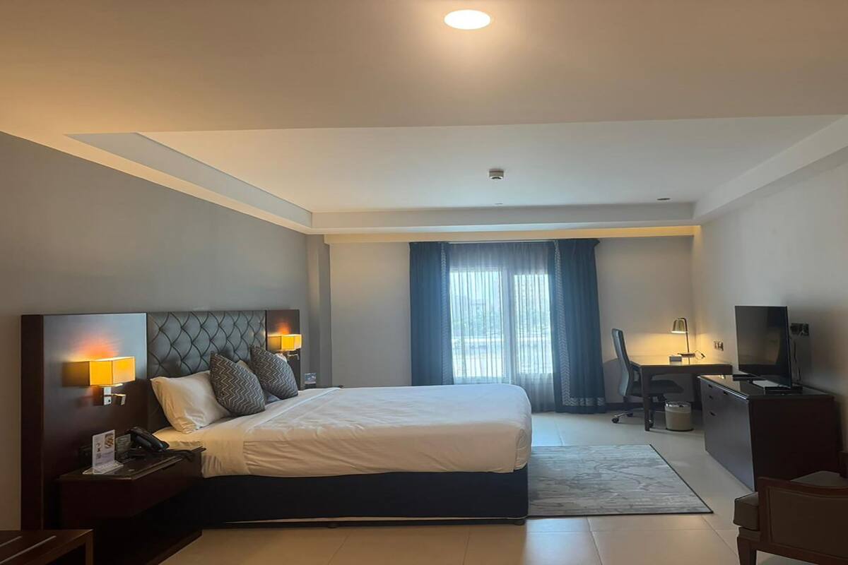 Une chambre d’hôtel avec un lit, un bureau, une télévision et une chaise.