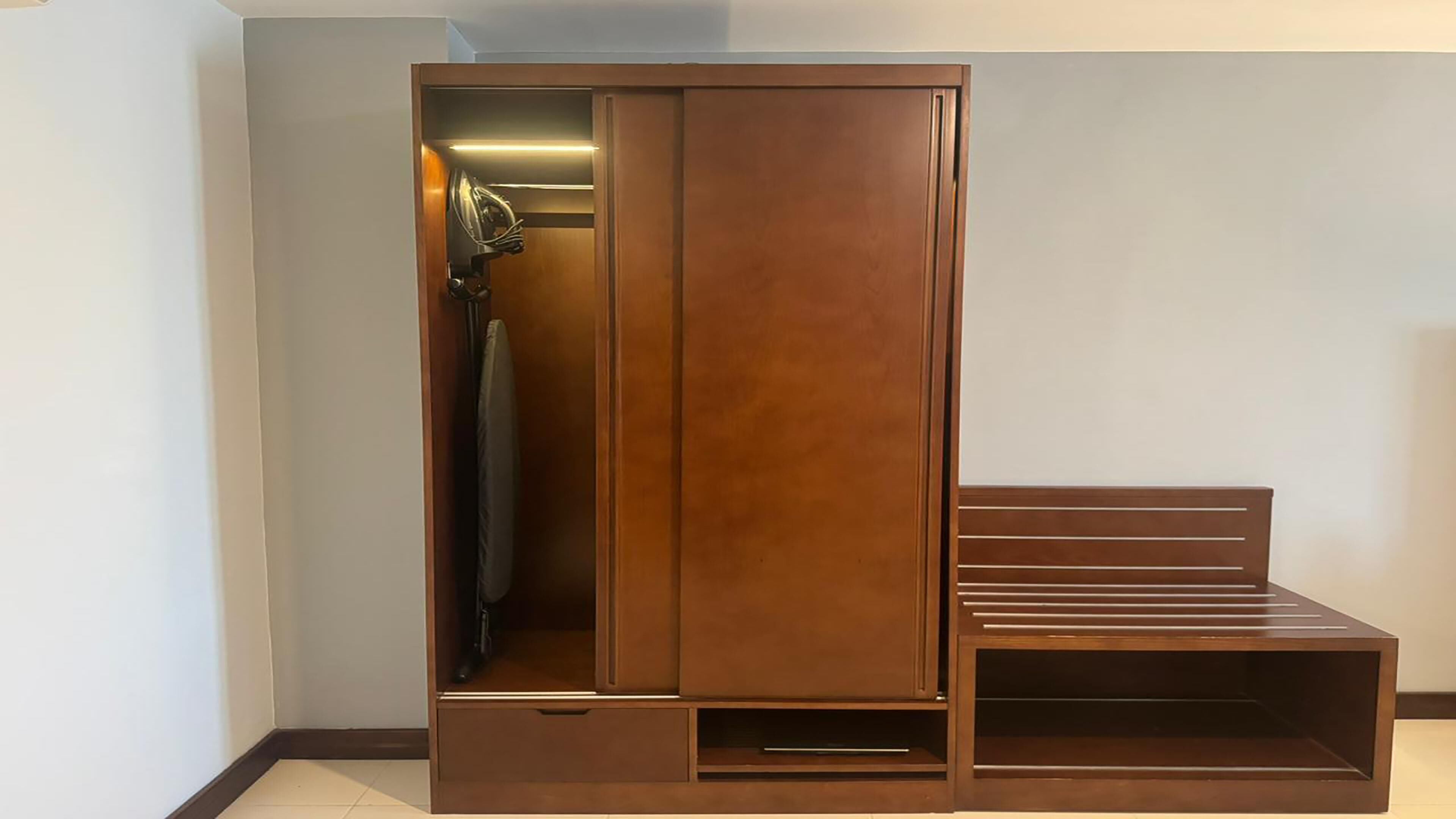 A wardrobe with a mirror, a hanging rack, and a built-in bench.