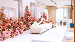 Een moderne hotelkamer met een wit bed, een witte bank en een grote bloemstelling.
