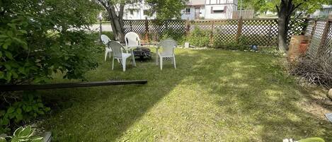 Een achtertuin met gazon, een houten terras en een witte schutting.